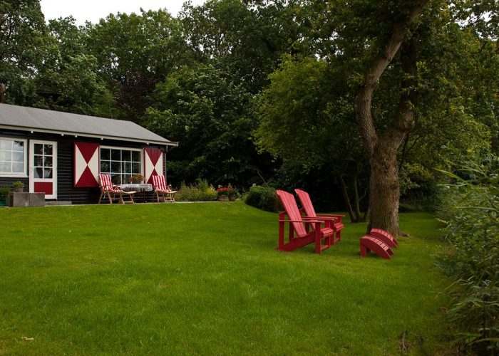Voorkant van een boshuis met uitzicht, voorzien van twee comfortabele zitstoeltjes voor een ontspannen ervaring in de natuur.