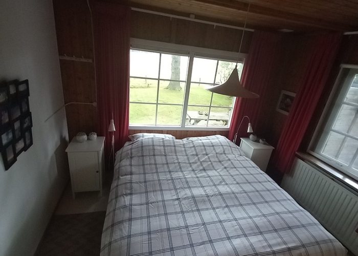Slaapkamer met tweepersoonsbed in het boshuis, simpel maar functioneel, met uitzicht op de natuur.