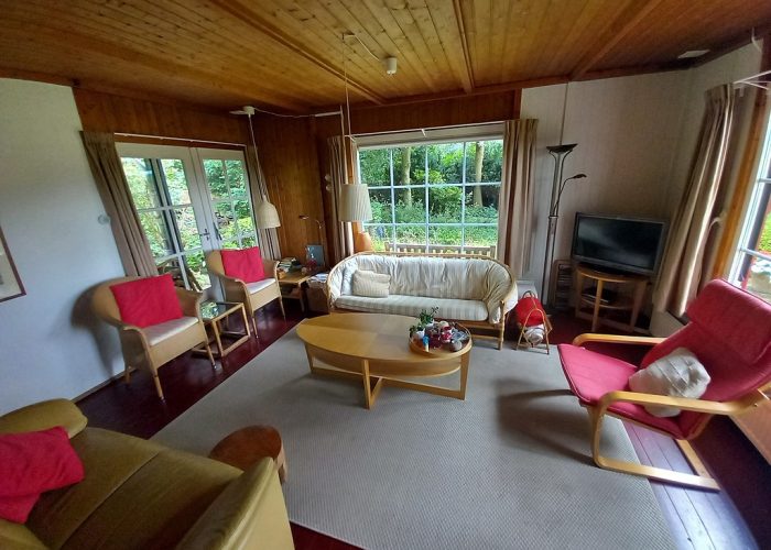 Woonkamer van het boshuis met uitzicht op de natuur, een gezellige en rustgevende ruimte.